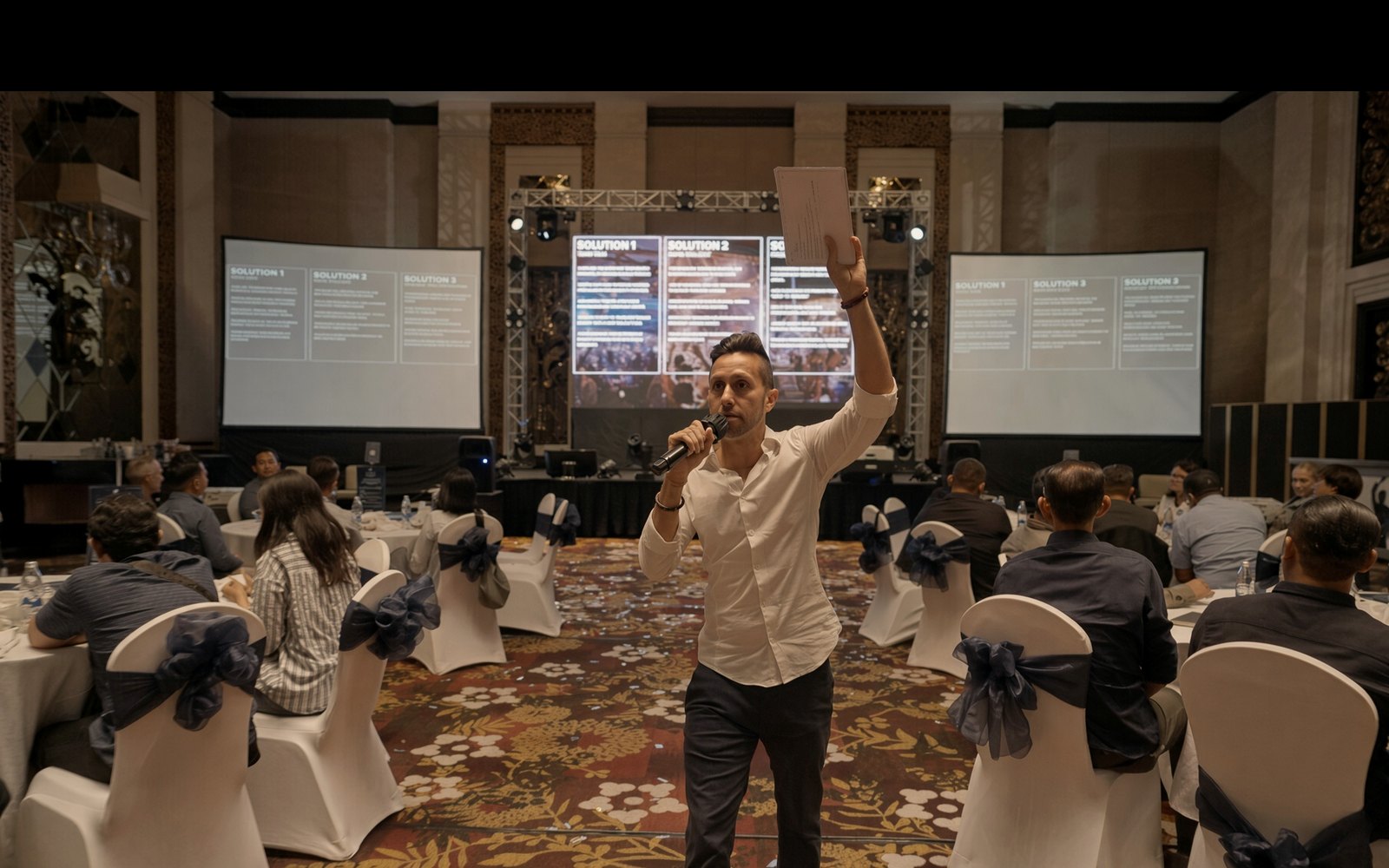 Cal Amir working the room with a microphone at a corporate event